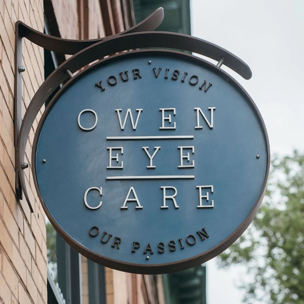 The exterior sign of Owen Eye Care hanging on the brick exterior of the building.