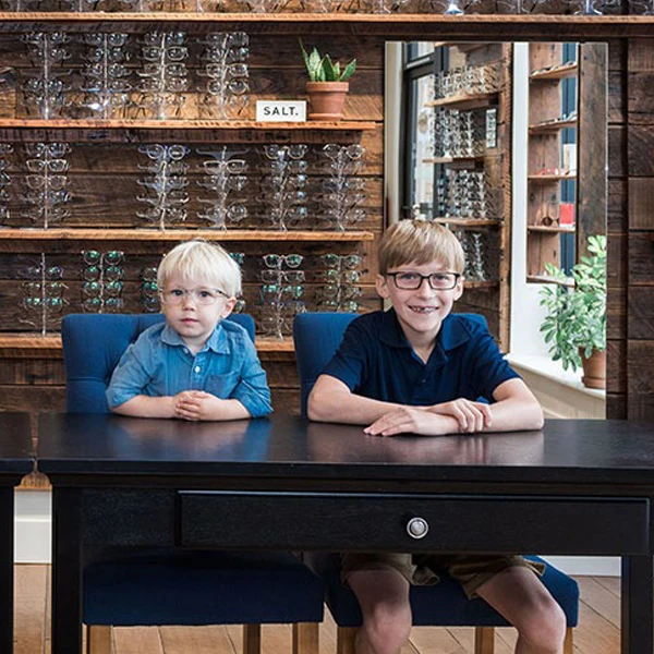 Children trying on frames in the Owen Eye Care lobby, smiling after finding the perfect fit