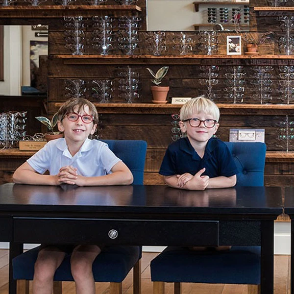 Children with glasses sitting in plush chairs in the Owen Eye Care after their appointment